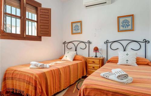 a bedroom with two beds with orange sheets and a window at Casa La Era in Frigiliana