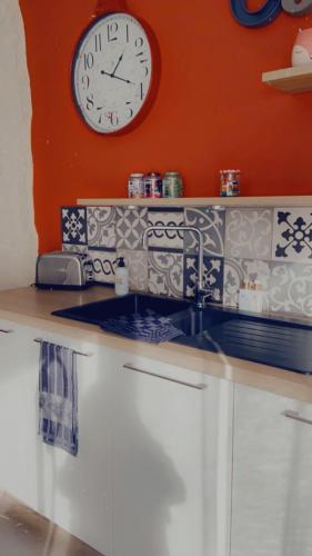 une cuisine avec un évier et une horloge murale dans l'établissement Ferme, à Tavaux