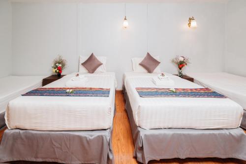 two beds in a room with white walls at Ibiza House Phi Phi in Phi Phi Don