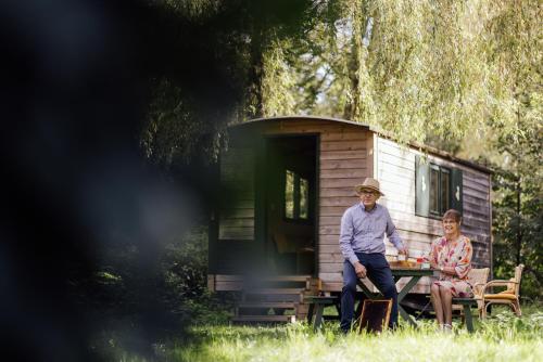 a man and woman sitting at a table in front of a tiny house at Hotel Het Buskruid in Lummen