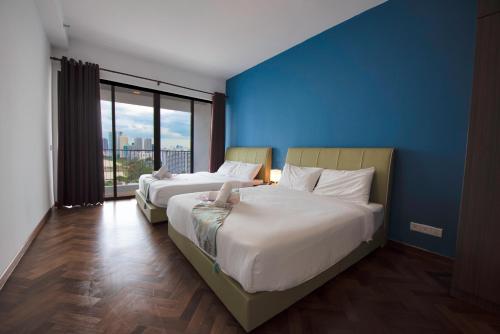 two beds in a room with a blue wall at The Landmark Seaview Suite in Tanjong Tokong