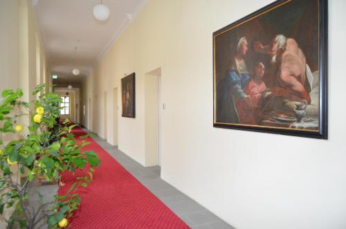 a hallway with a painting on the wall and a red carpet at Gästehaus im Priesterseminar Salzburg in Salzburg