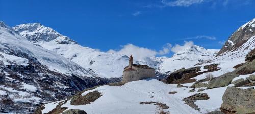un petit bâtiment sur une montagne enneigée avec des montagnes enneigées dans l'établissement Chalet La Clavarine, à Bonneval-sur-Arc
