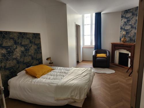 - une chambre avec un lit, une chaise et une cheminée dans l'établissement La Grenette, à Charolles