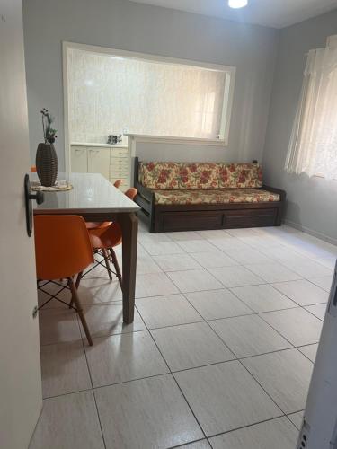 a living room with a bed and a table and chairs at Apartamento Beira Mar! in Capão da Canoa