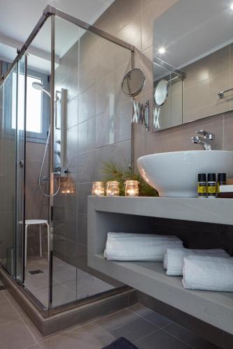 a bathroom with a glass shower and a sink at The Gardens Gallery Hotel in Xylokastron