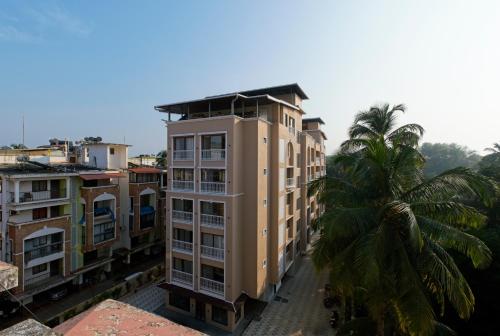 a tall building with a palm tree in front of it at Brisa by StayALYF in Candolim
