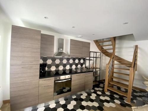 une cuisine avec des placards en bois et un escalier avec un sol en damier dans l'établissement Maison de location - Les 4 Saisons, à Saint-Denis-sur-Sarthon