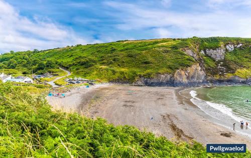 a beach with people on the sand and the ocean at 3 Tower Hill in Dinas
