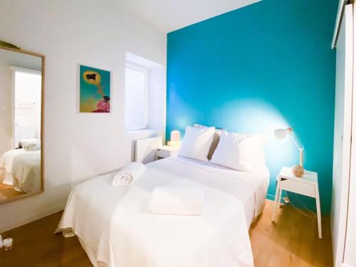 - une chambre avec un lit blanc et un mur bleu dans l'établissement Le petit Musée À 2 pas des Arènes, à Nîmes