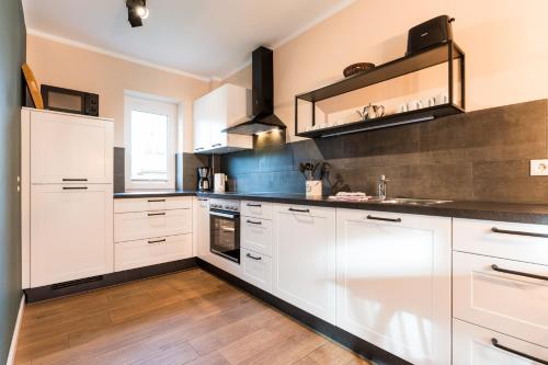 a kitchen with white cabinets and wooden floors at Backhaus 3 in Staberdorf