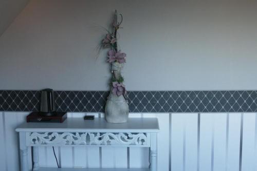 a white table with a vase with flowers on it at Quartier 10 HA10 in Sögel