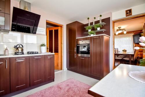 a kitchen with wooden cabinets and a pink rug at Marysieńka Pokoje Hrube Wyżne 12A in Zakopane