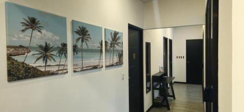a hallway with four paintings of the beach at Villa Elenita - Pura Vida in Parrita