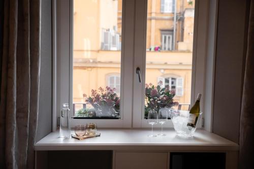 a window with glasses and flowers on a ledge at Nineteen House in Frascati