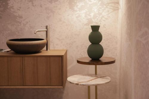 a bathroom with a sink and a vase on a stool at Nineteen House in Frascati