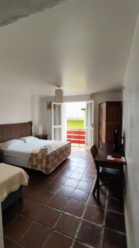 a bedroom with a bed and a table and a desk at Hotel Camboa Antonina - PR in Antonina