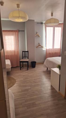 a room with a bed and a chair and two windows at B&B l'Edelweiss in Vallouise
