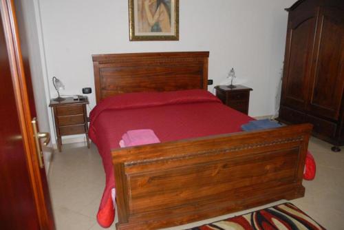マツァーラ・デル・ヴァッロにあるOasi Tortuga Residence Appartamento 4 con Piscina e Barbecue h24のベッドルーム1室(木製ベッド1台、赤いベッドカバー付)