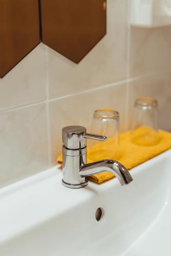 a bathroom sink with a faucet and two glasses at Hotel Het Buskruid in Lummen
