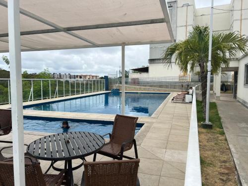 a patio with a table and chairs and a swimming pool at Apto mobiliado e aconchegante - 3 quartos e 4 camas - Lazer completo e localização privilegiada in João Pessoa