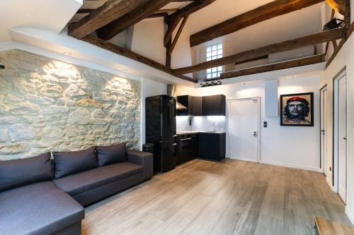 un salon avec un canapé et un mur en pierre dans l'établissement Appartement Place des Vosges, Marais Bastille, à Paris
