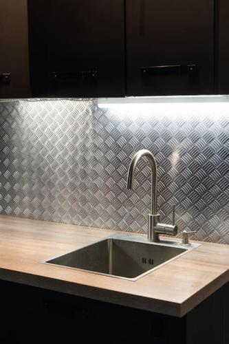 - un évier dans la cuisine dotée d'un mur en acier inoxydable dans l'établissement Appartement Place des Vosges, Marais Bastille, à Paris