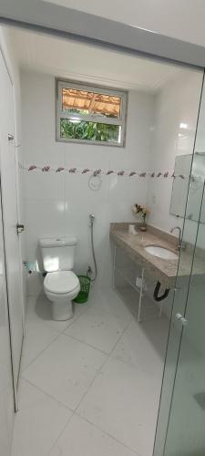 a bathroom with a toilet and a sink and a window at Chácara Rosa do Deserto in Vila Velha