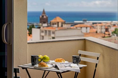 a table with bread and fruit on a balcony at Luxury View Apartment Funchal CENTRAL free parking FAMILIES in Funchal