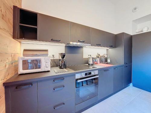 une cuisine avec des placards bleus et un four micro-ondes sur le comptoir dans l'établissement Snow Roc B302, à Saint-Jean-dʼAulps