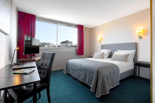 a hotel room with a bed and a desk and a window at Bristol Logis Cit'Hotel Périgueux Centre in Périgueux