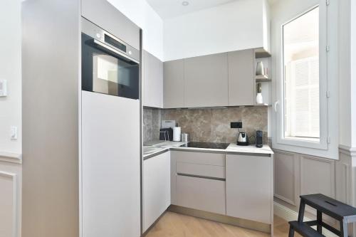 une cuisine blanche avec des armoires blanches et un évier dans l'établissement #6 1BDR Buffa 2 min from the beach and Negresco,central AC Balcony, à Nice