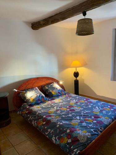 a bedroom with a bed with a colorful comforter and a lamp at Duplex T3 climatisé centre terrasse parking payant in Manosque