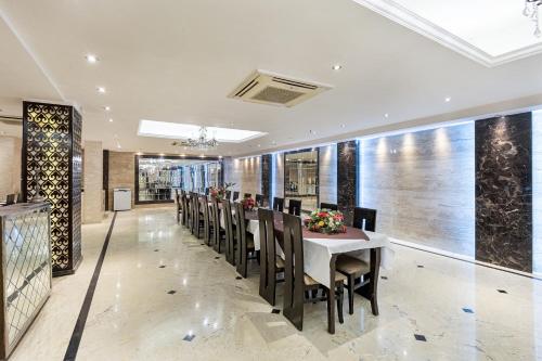a dining room with a long table and chairs at Alaya Stays Hotel Emperor Palms in New Delhi