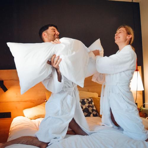 a man and a woman playing with pillows on a bed at Ibis Styles Crolles Grenoble A41 in Crolles