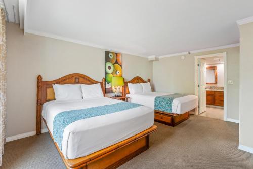 a bedroom with two beds and a bathroom at Luana Waikiki Hotel & Suites in Honolulu