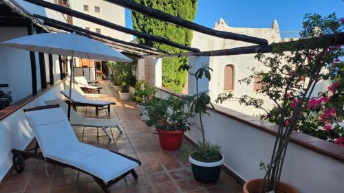 a balcony with chairs and an umbrella and plants at Hotel Pop in Cala Gonone