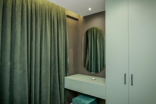 a bathroom with a green shower curtain and a mirror at Vollgaapartment2 in Durrës