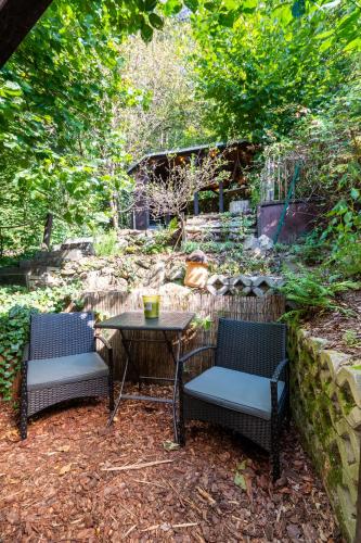 a patio with two chairs and a table and a stone wall at Haus am Wald in Bad Schandau
