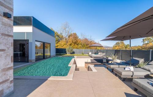 a backyard with a swimming pool with chairs and an umbrella at Nice Home In Labin With Sauna in Labin