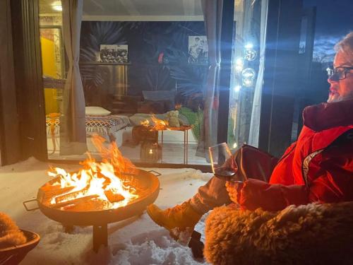 a person sitting next to a fire in a room at Tiny Haus #02 Cube 18 Seefeld in Seefeld