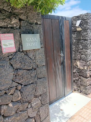a wooden door in a stone wall with a sign at Casa Jaime in Puerto del Carmen