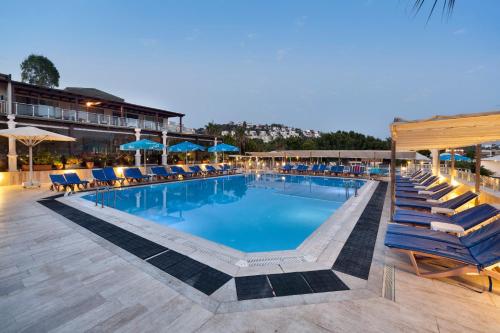 a swimming pool with chairs and umbrellas on a resort at Golden Age Hotel Yalıkavak Bodrum in Yalıkavak