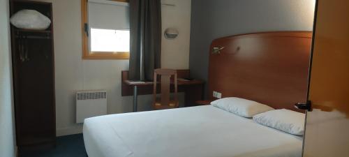 a bedroom with a white bed with a wooden headboard at Welcomotel Beauvais Aéroport in Beauvais