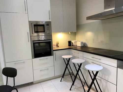 a kitchen with white cabinets and stools in it at Luxury Serviced 3-Bedroom Flat in Vienna's 1st District in Vienna
