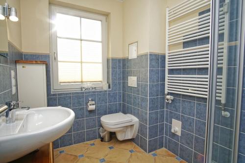 ein blau gefliestes Badezimmer mit Toilette und Waschbecken in der Unterkunft Strandvilla Böck FeWo 10 strandnah, Balkon, Meerblick in Glowe