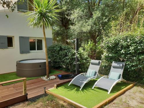 2 chaises sur une parcelle d'herbe à côté d'une baignoire dans l'établissement Villa Namibia - Jacuzzie - 500m Plage et Lac, à Seignosse