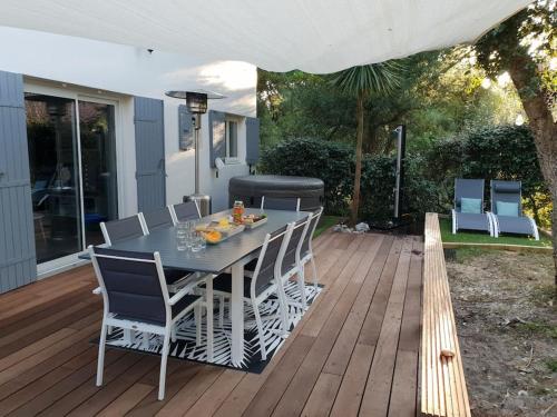 une table et des chaises sur une terrasse avec un parasol dans l'établissement Villa Namibia - Jacuzzie - 500m Plage et Lac, à Seignosse