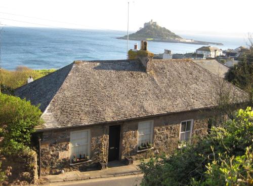 an old stone house with the ocean in the background at Romantic cottage with fantastic coastal views in Marazion