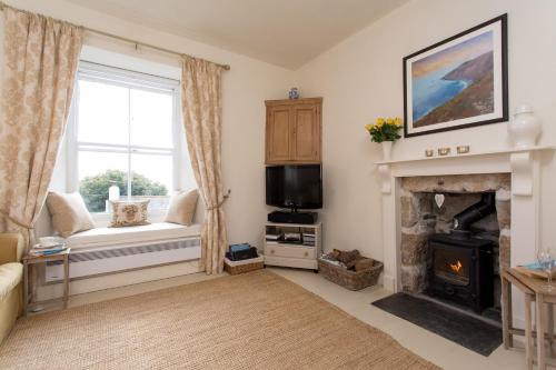 a living room with a fireplace and a window at Romantic cottage with fantastic coastal views in Marazion